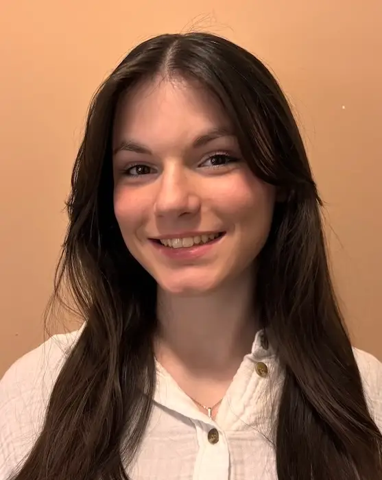 Jeune femme souriante en chemise blanche.