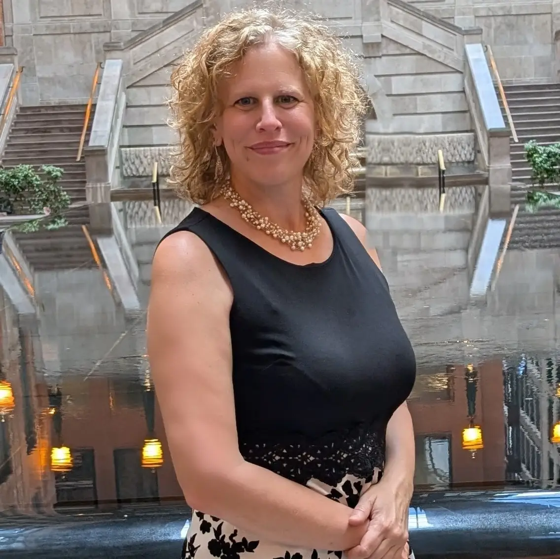 Femme souriante devant une fontaine intérieure et un escalier