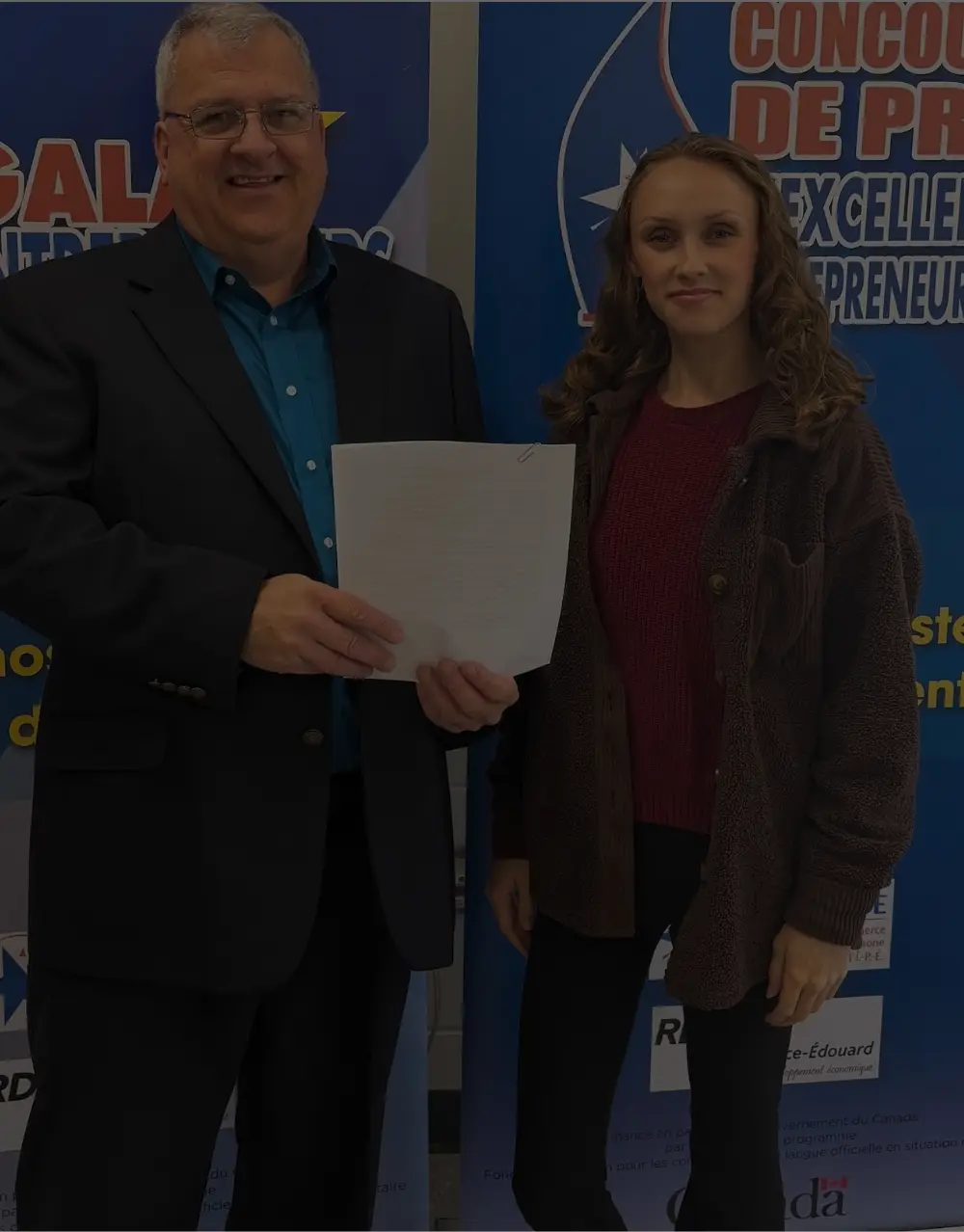 Two people present a document in front of promotional banners