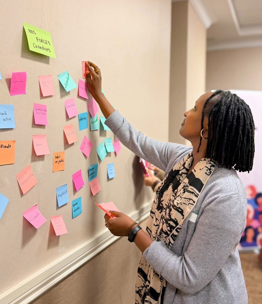Participante ajoutant un post-it à un mur collaboratif
