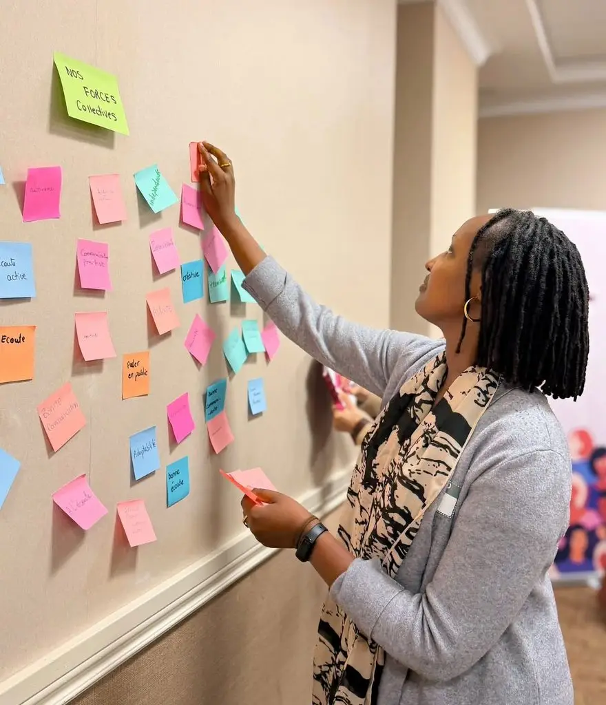 Participante ajoutant un post-it à un mur collaboratif