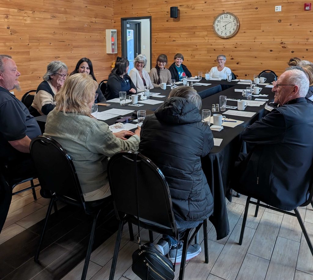 Groupe réuni autour de tables lors d’une rencontre communautaire