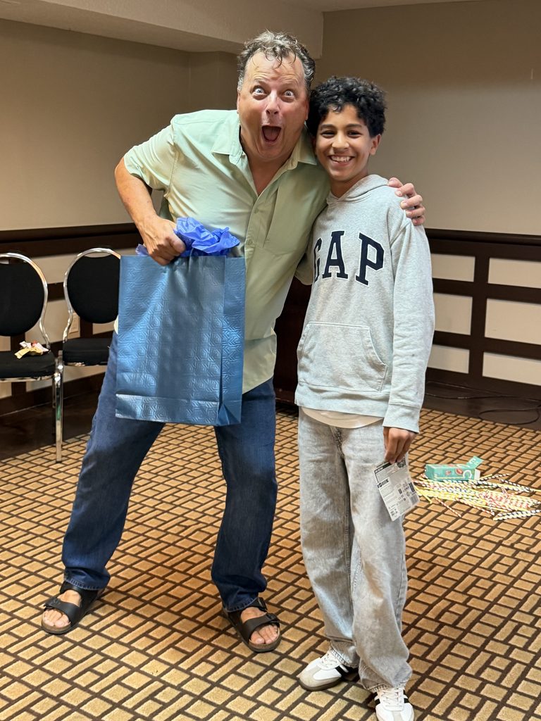 Homme enthousiaste offrant un sac-cadeau à un adolescent souriant
