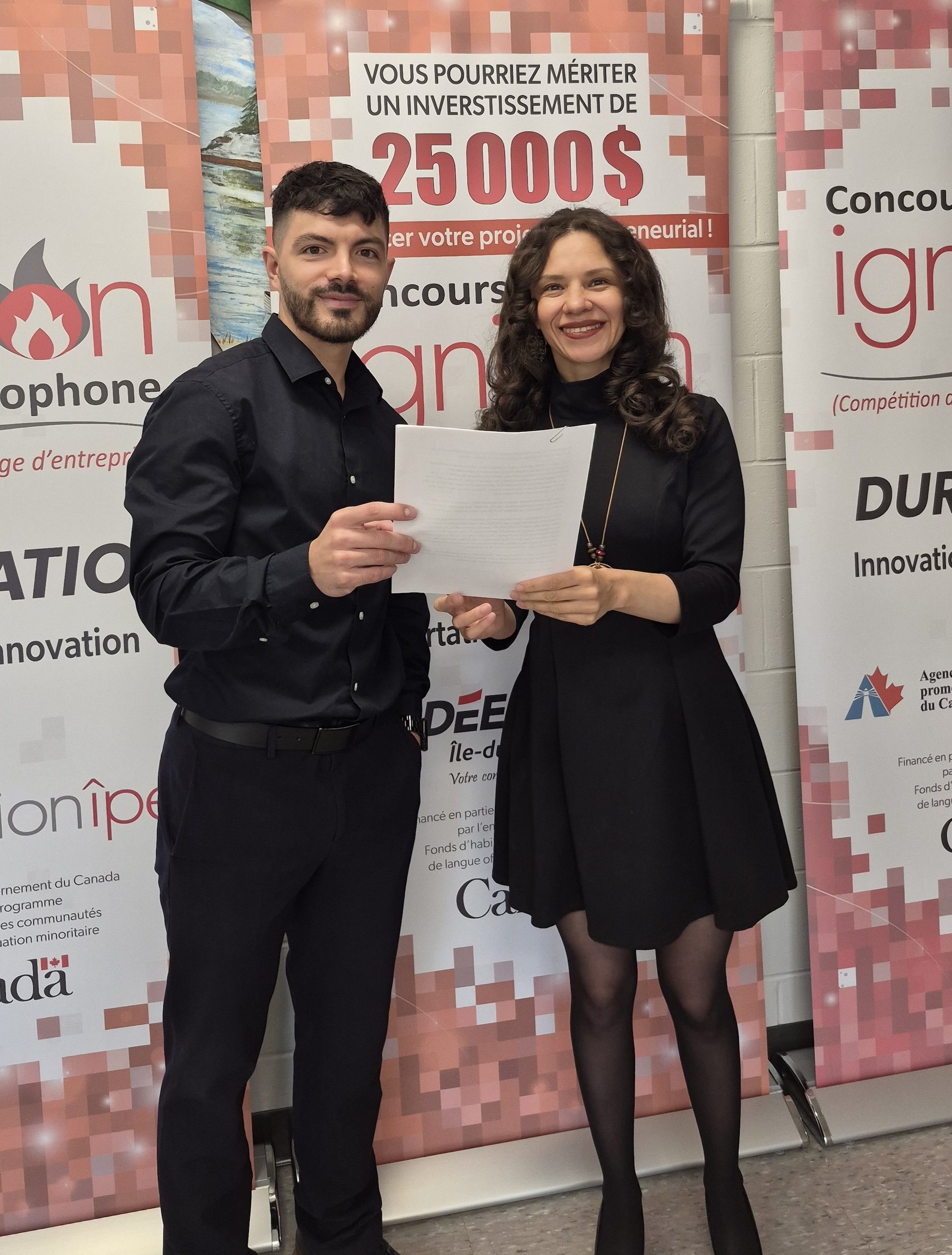Deux personnes présentent un document devant une bannière de concours.