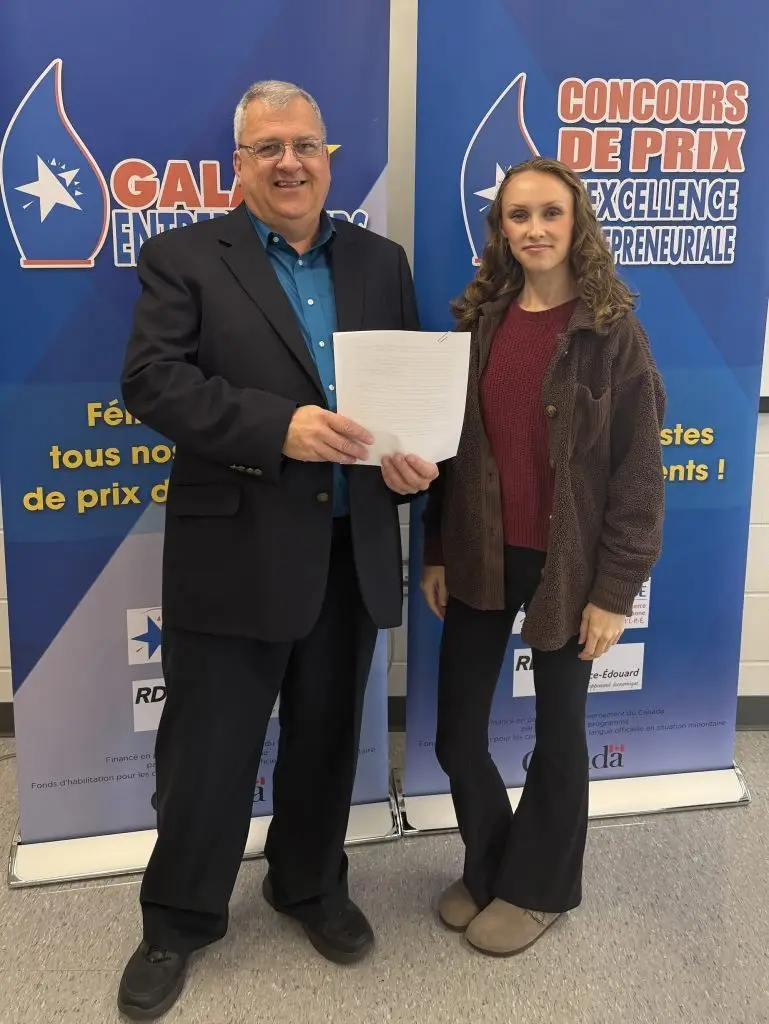 Deux personnes présentent un document devant bannières de concours.